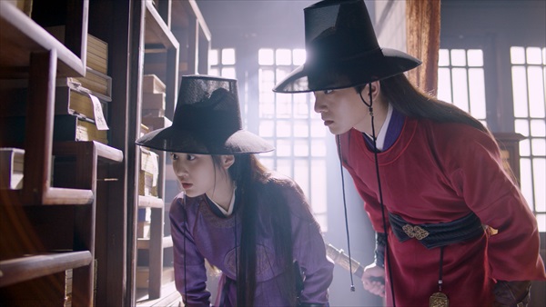 柱に刺した針をのぞき込む2人