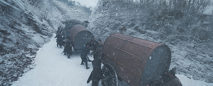 吹雪の中、馬車を押す人々